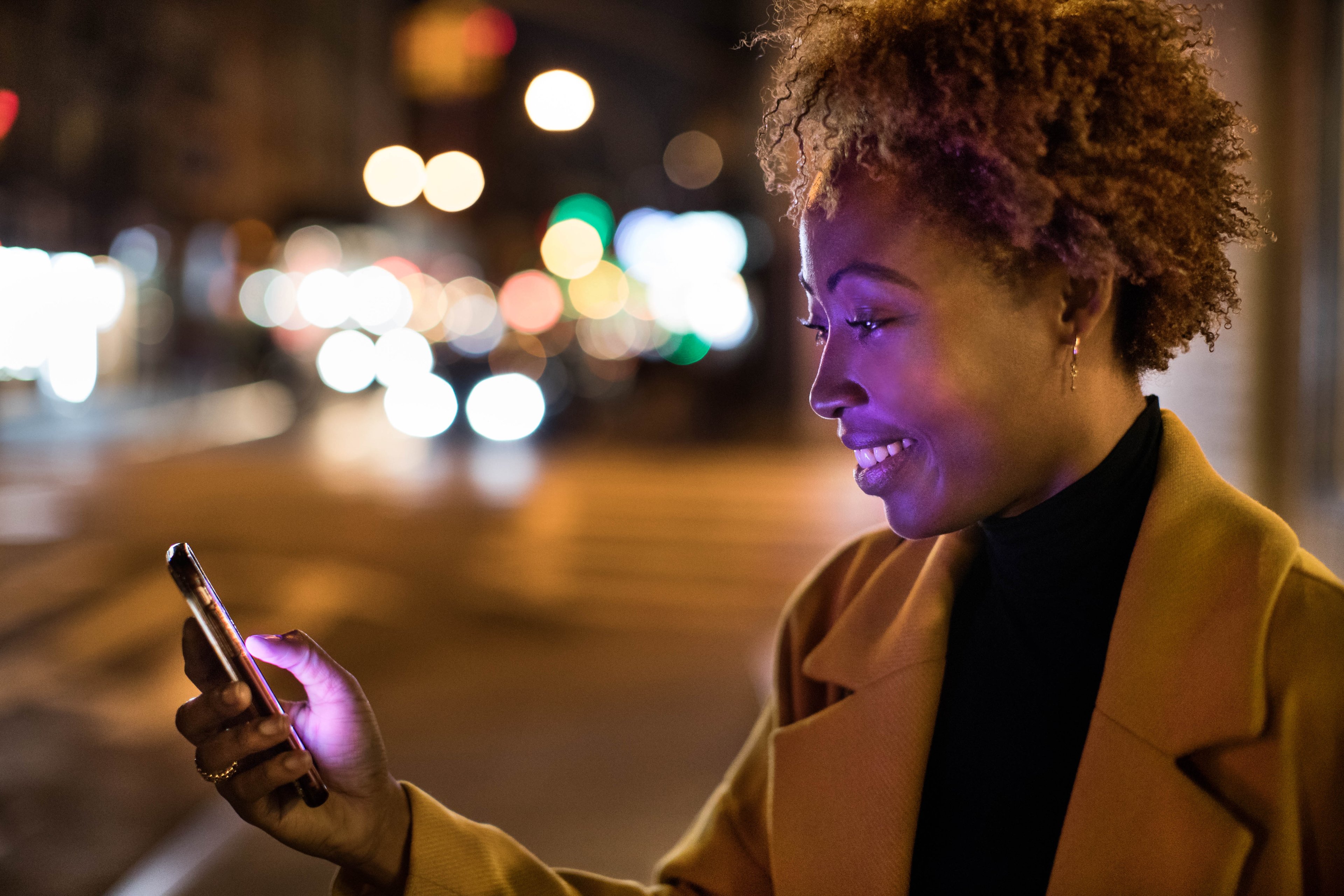 Woman using the Lyft app to hail a ride at night