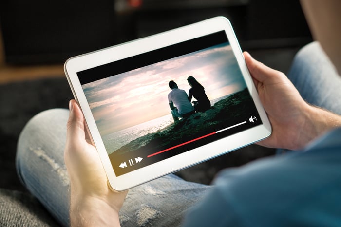 A person holding a tablet streaming a video.