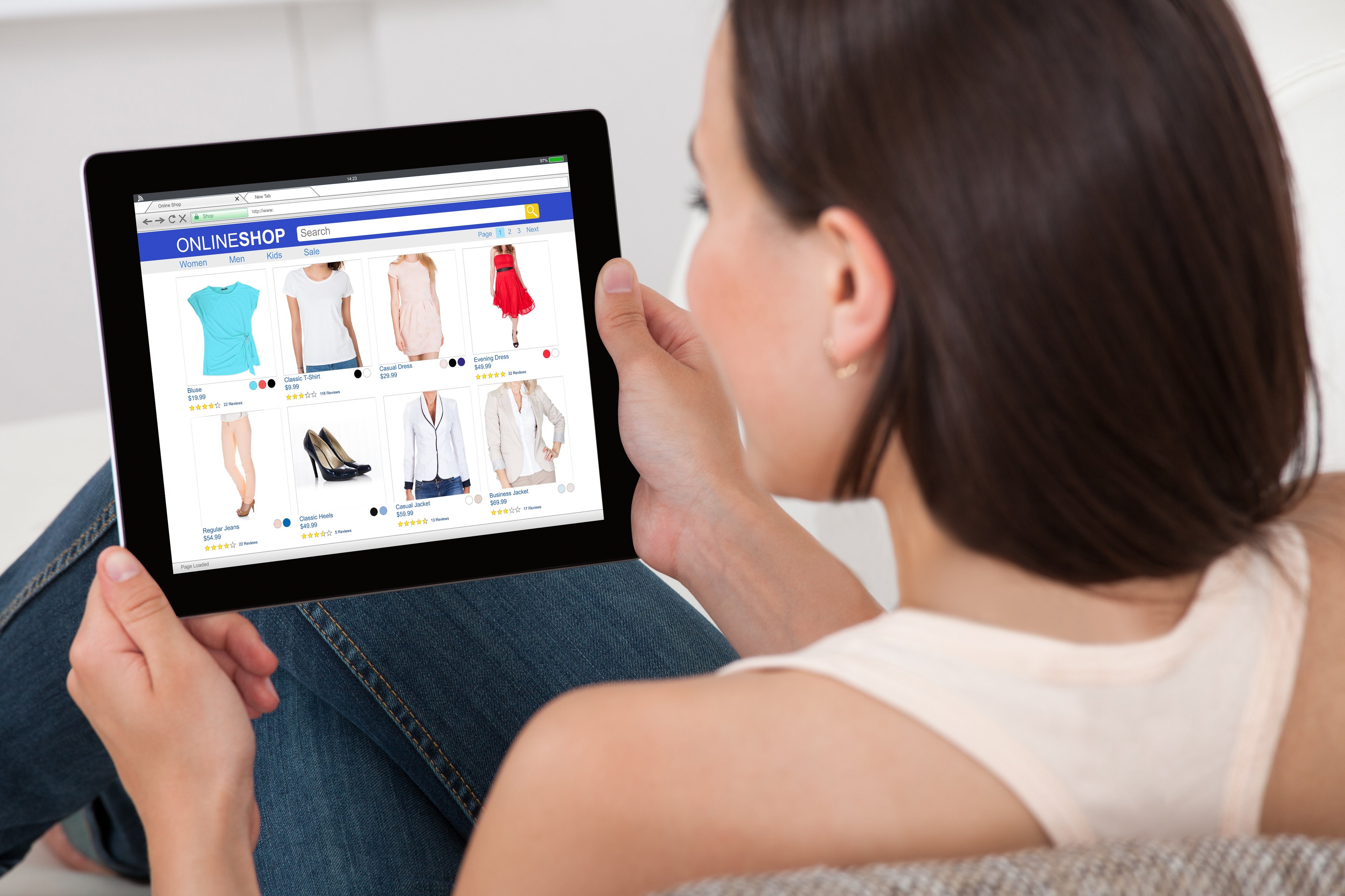 A woman shopping for clothes online using a tablet. 