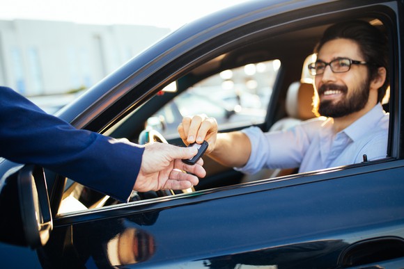 Salesman handing customer keys to a car.