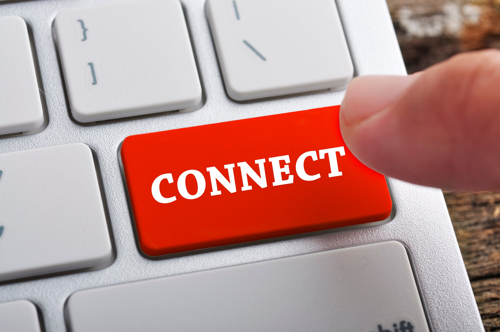 A finger hovers over a laptop keyboard where the "enter" key has been replaced by a red button labeled "connect"