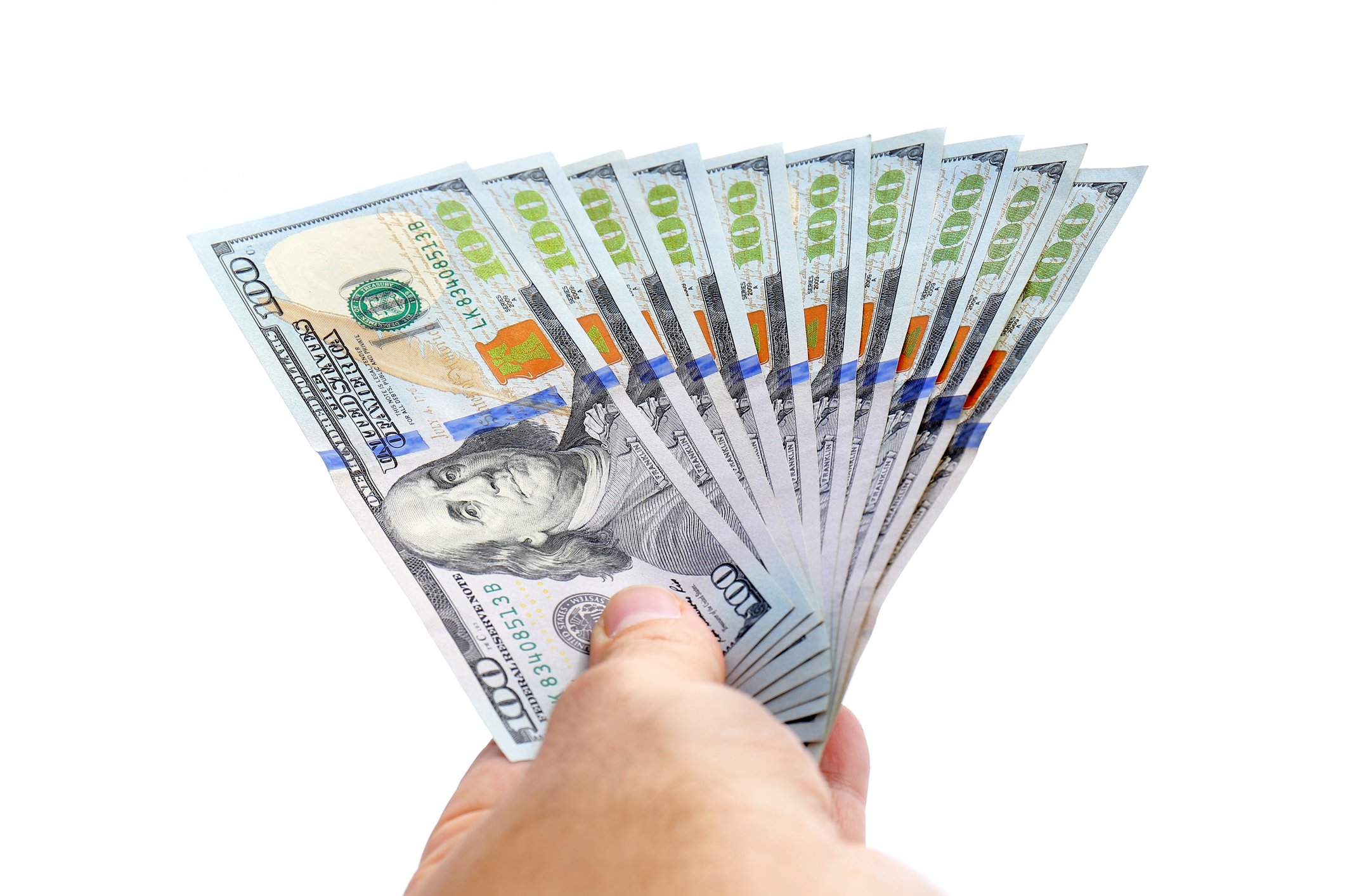 A hand is holding a bunch of hundred dollar bills, fanned out.