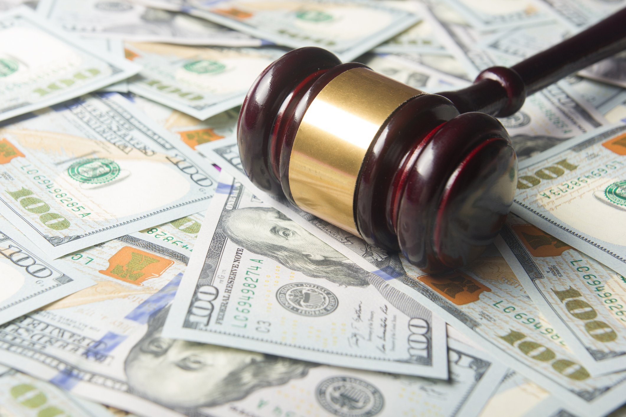 A gavel rests on a bunch of $100 bills.