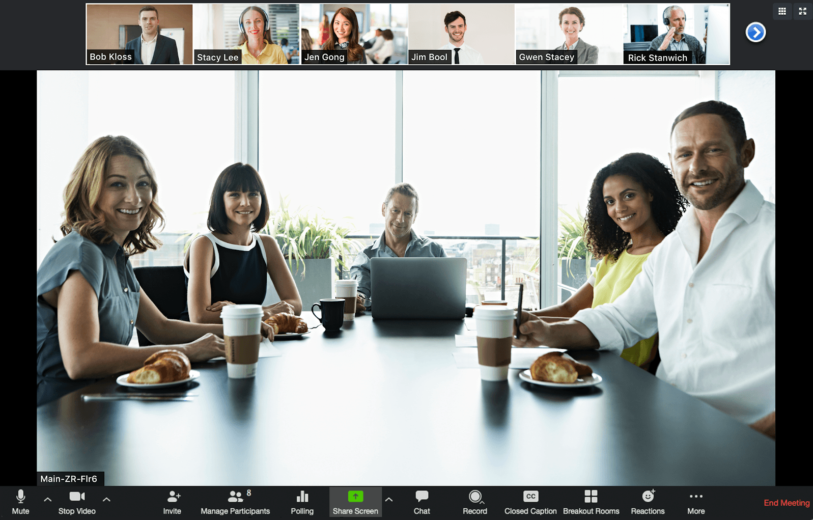 A screen cap from a Zoom video meeting with a group of attendees sitting in a conference room.