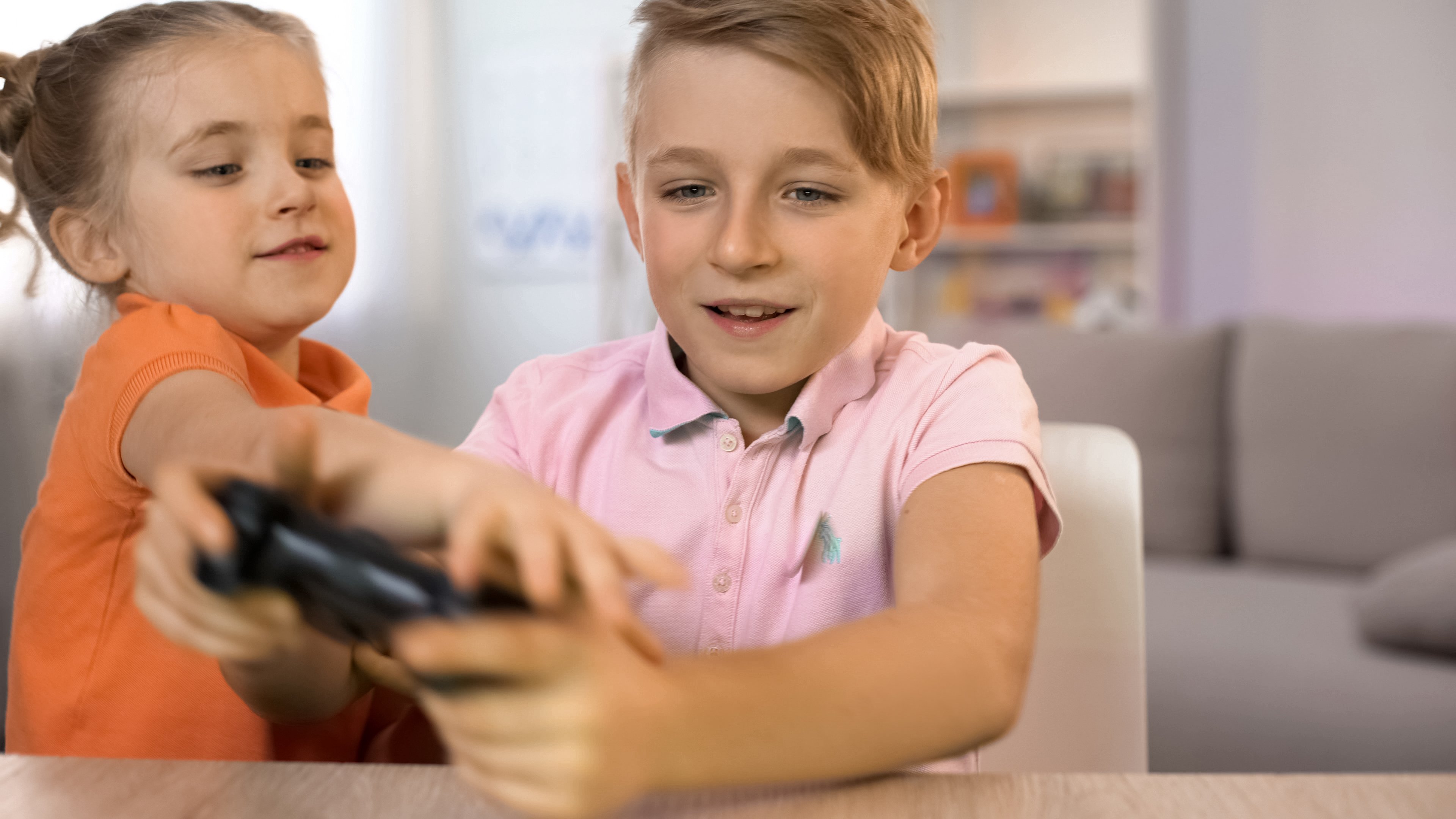 Two children fight over a video game controller. 