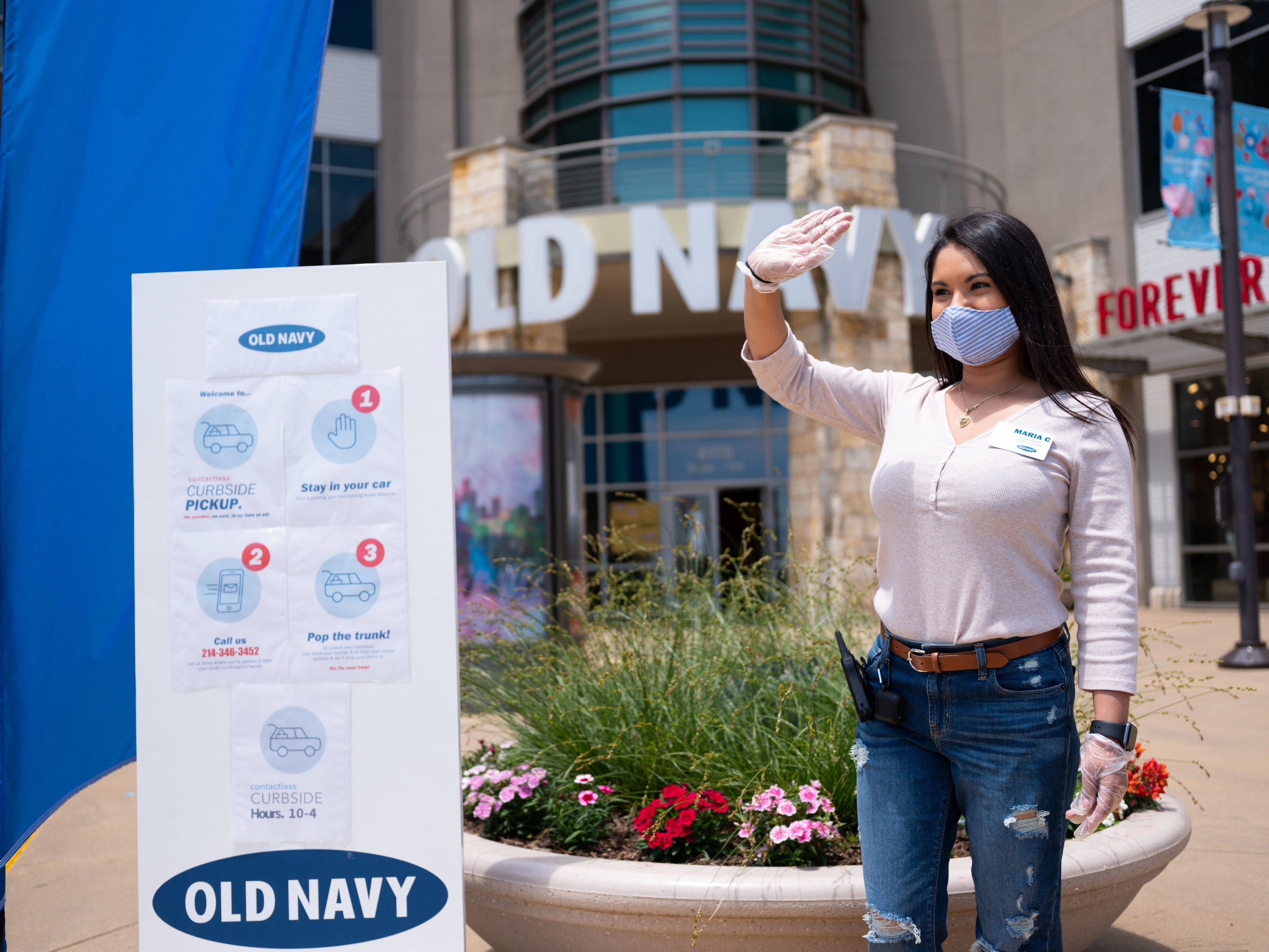 An Old Navy employee stands outside a store curbside pickup location.
