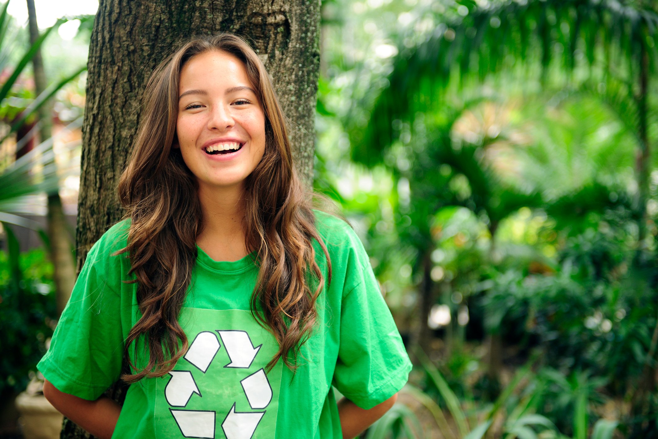 Smiling young woman wearing green t-shirt with recycle symbol.
