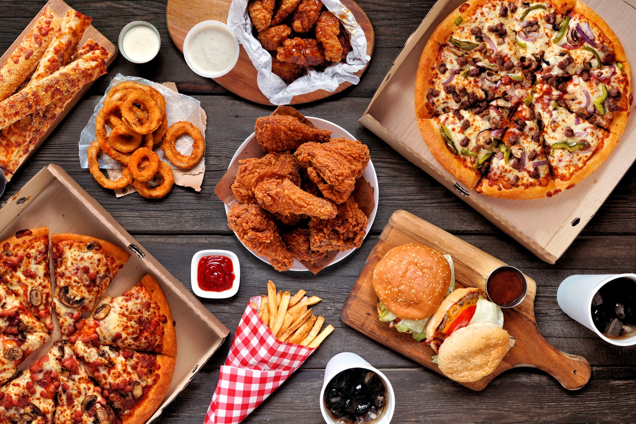 Pizza, fried chicken, burgers, and other fast food on a table.