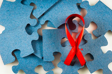 Red ribbon with blue jigsaw puzzle pieces