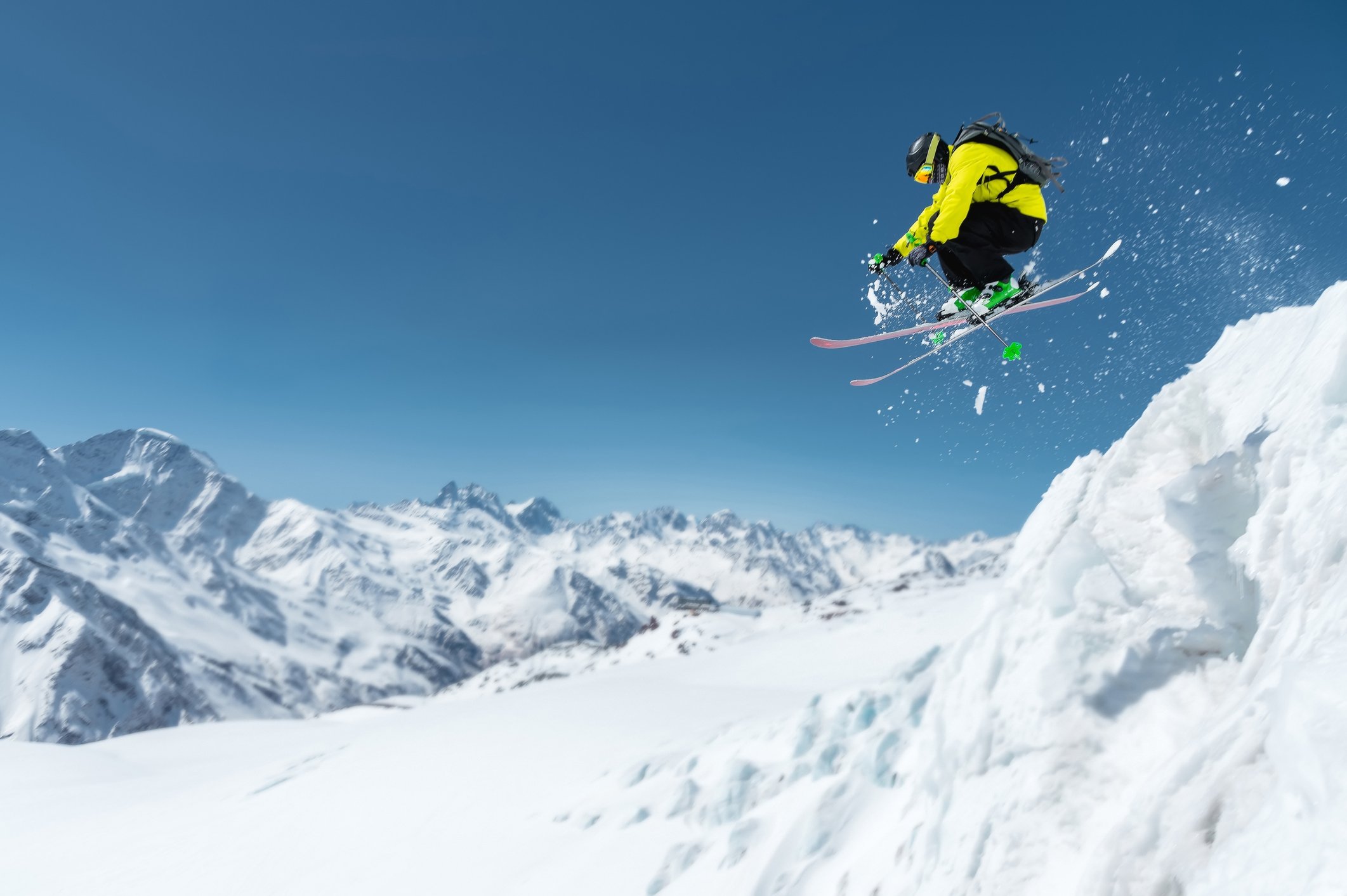 Skier jumping off small cliff on a mountain. 