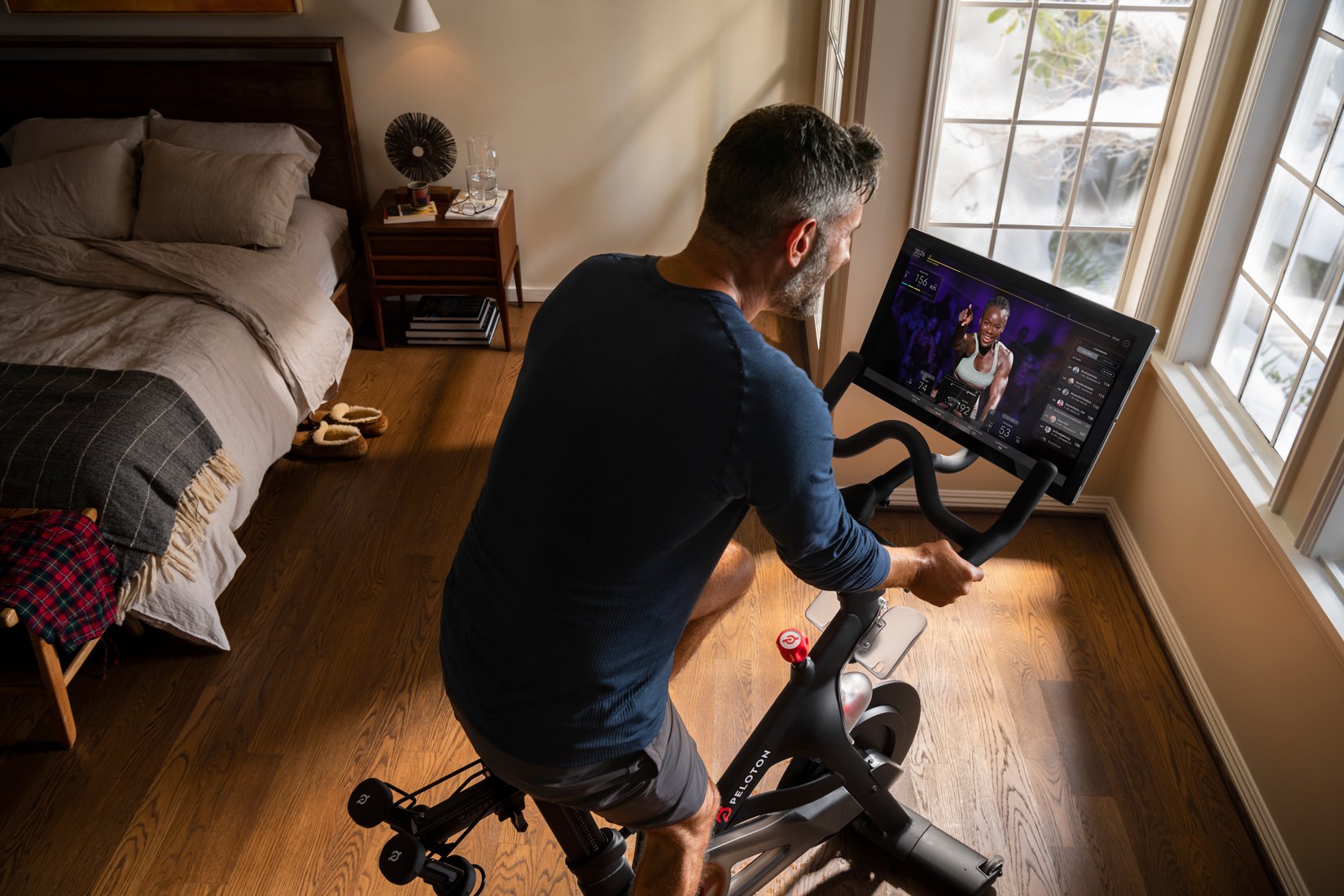 Middle-aged man riding a Peloton bike in a bedroom.