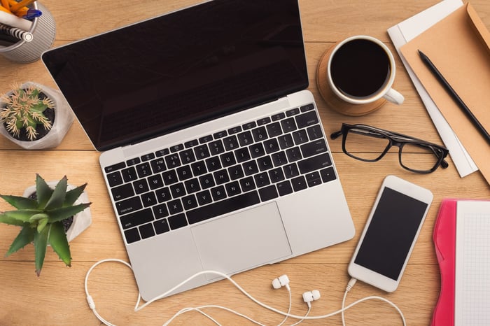 Apple laptop and iPhone sitting on a desk. 