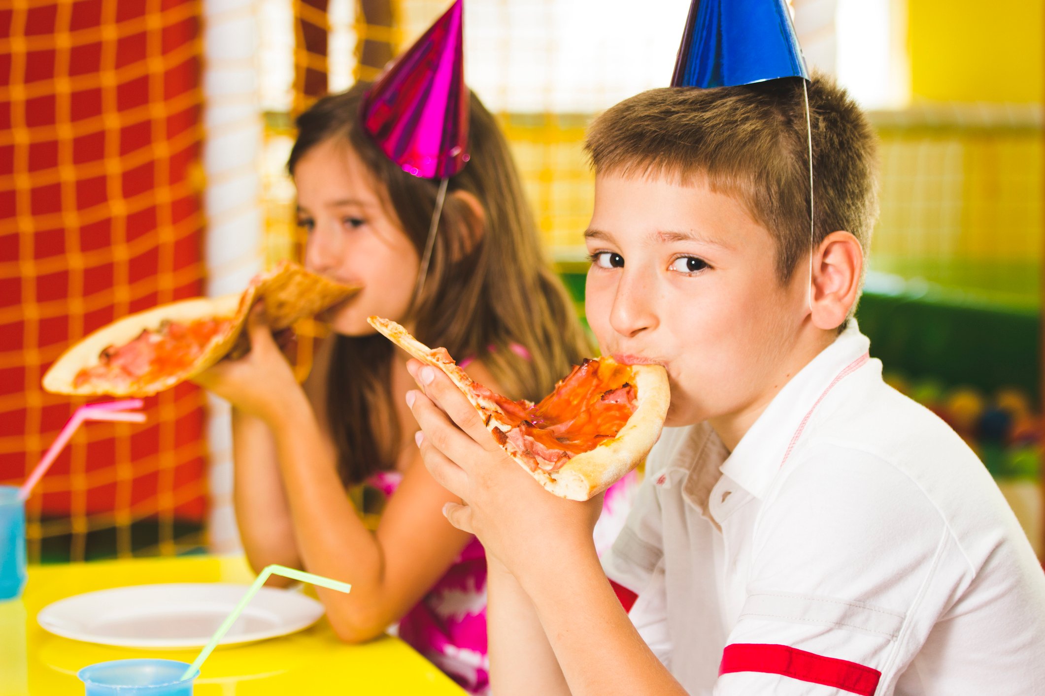 two kids at a birthday pizza party eating pizza