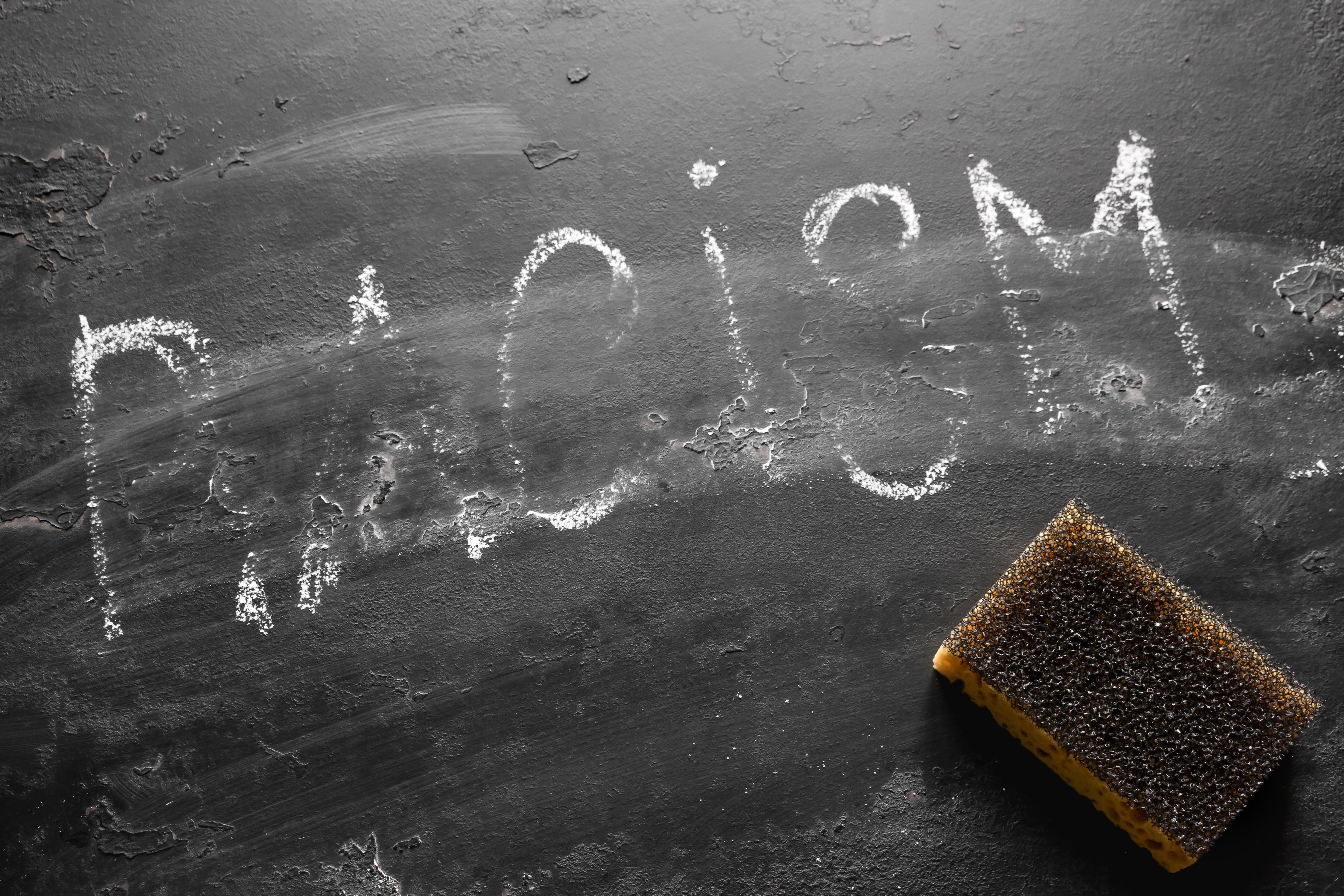 Black board with the word racism being erased. 