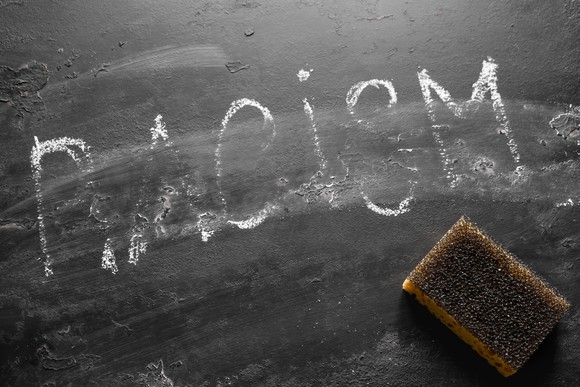 Black board with the word racism being erased. 