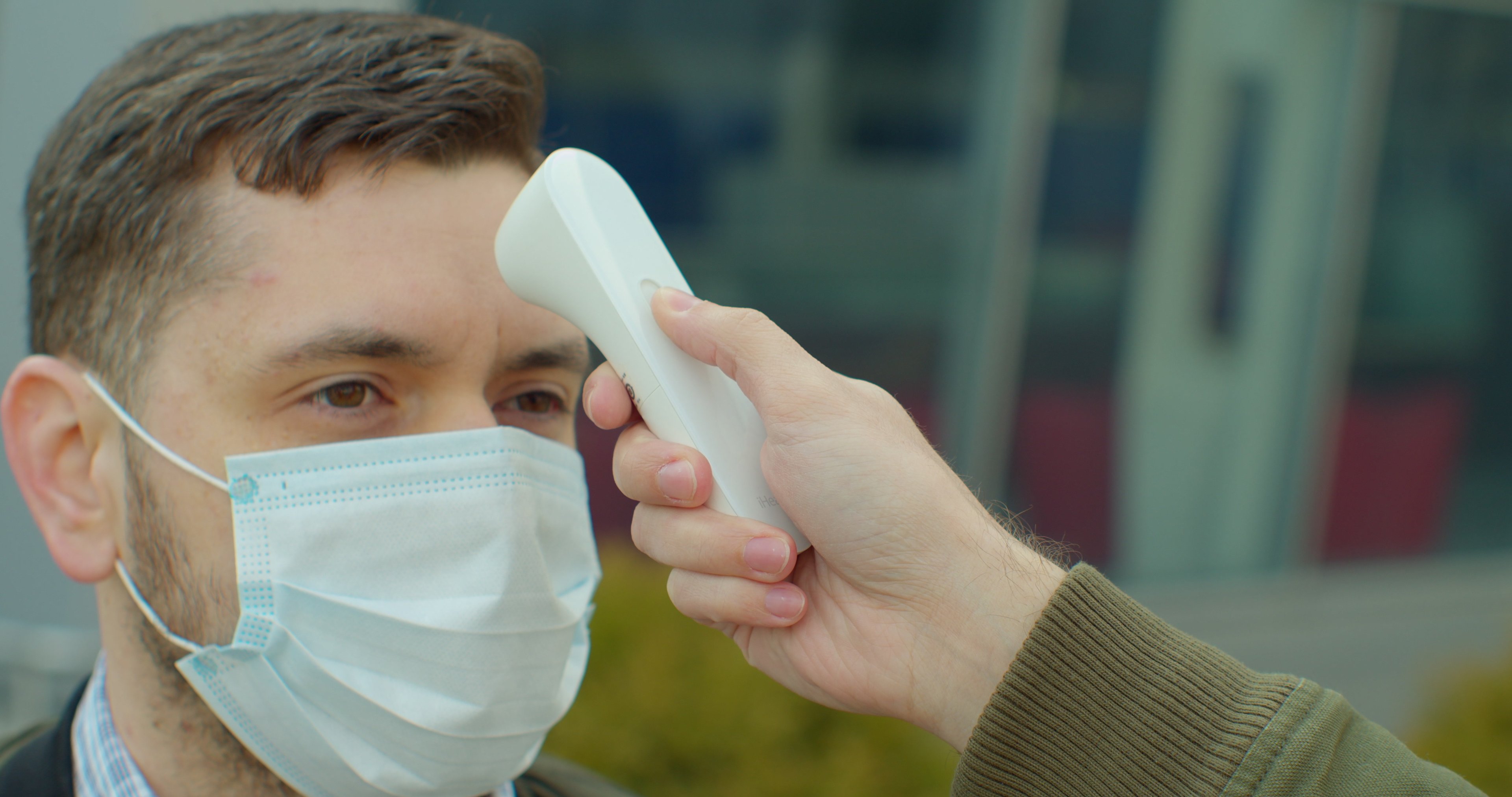 A person wearing a mask has his temperature checked.