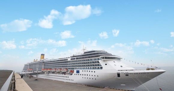 Carnival-branded cruise ship docked on a mostly sunny day, with a few passengers walking on the dock.