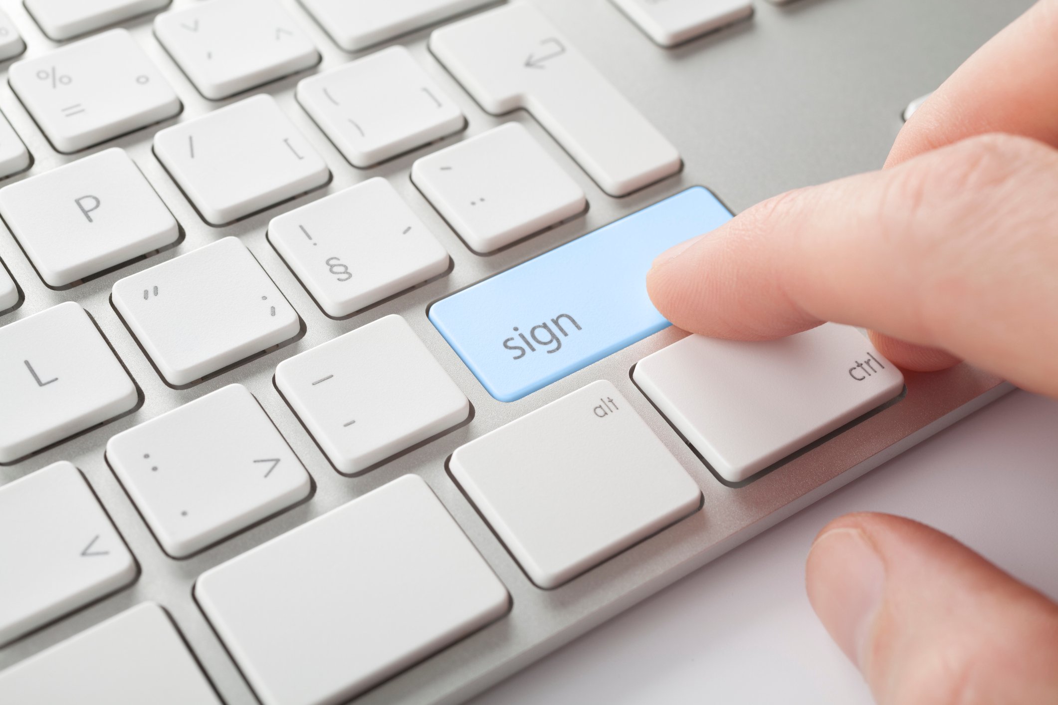 A finger pressing a computer key marked with the word "sign"