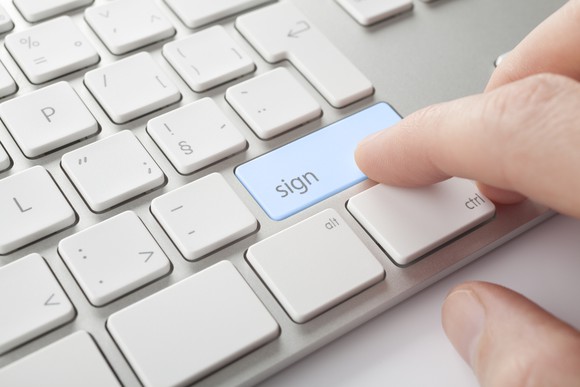 A finger pressing a computer key marked with the word "sign"