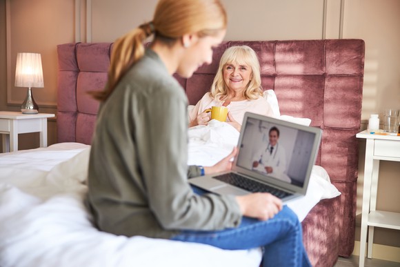 Nurse having consultation with doctor at patient's home. 