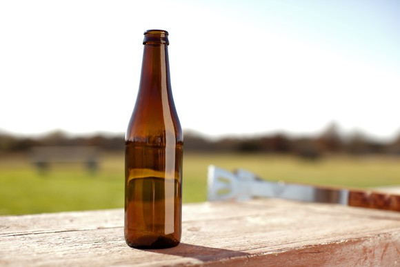 A single glass bottle sits on a table outside