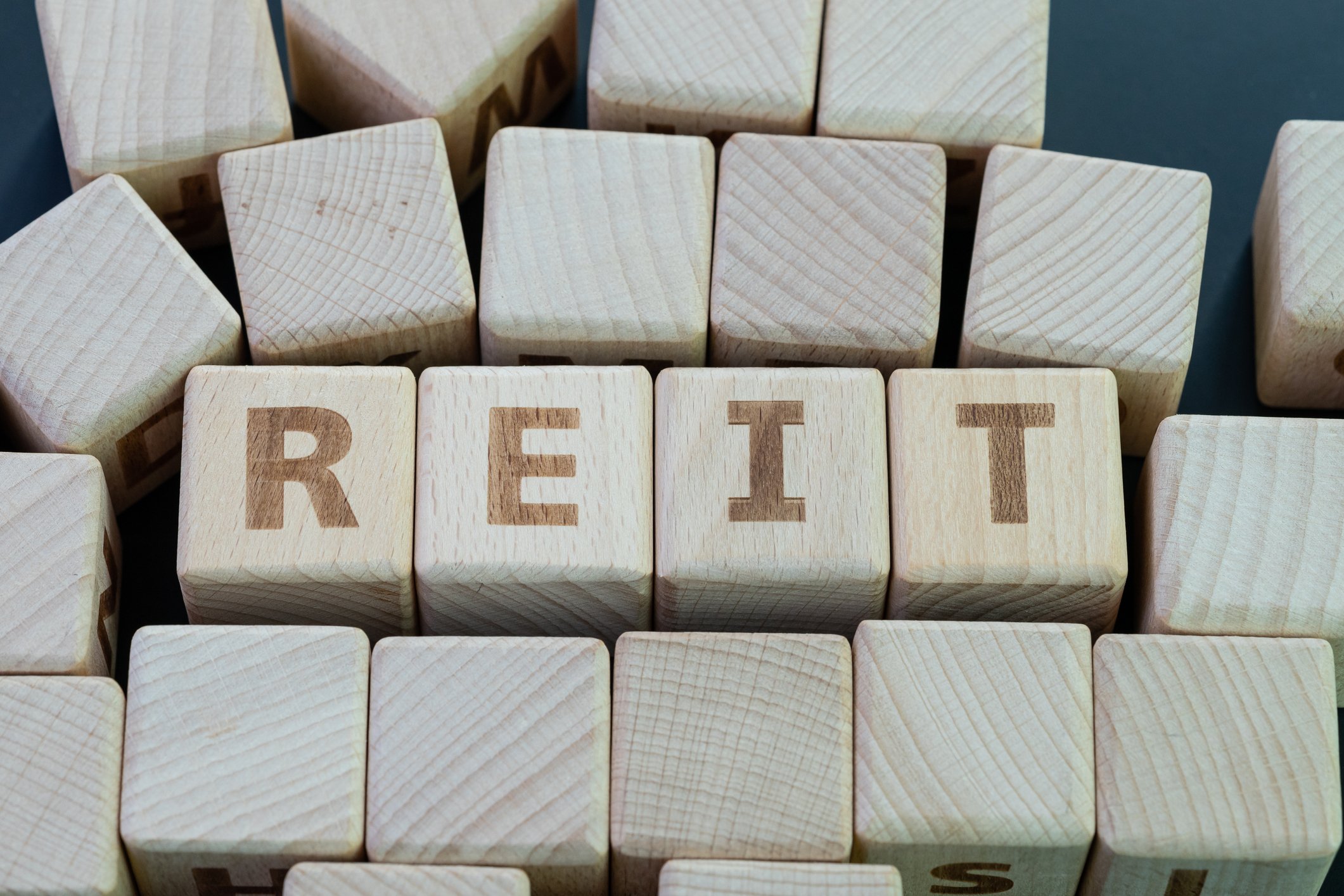 The word REIT spelled out in wooden blocks.
