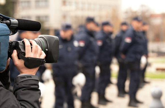 A cameraman filming a group of police officers.