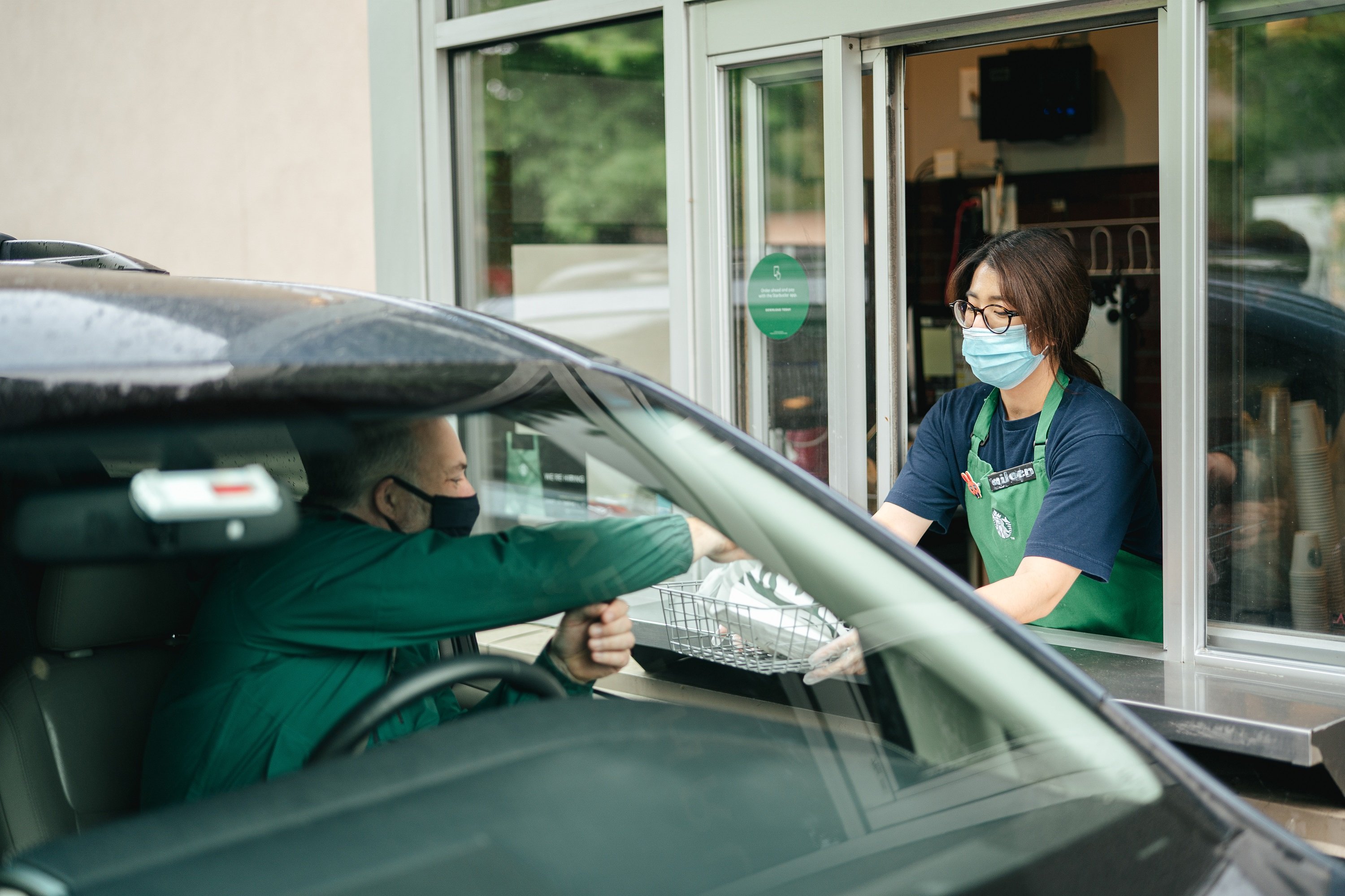 Starbucks worker serving a customer in drive-thru.