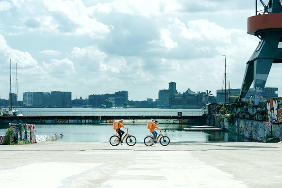 Just Eat Takeaway.com delivery personnel ride bikes while delivering food.