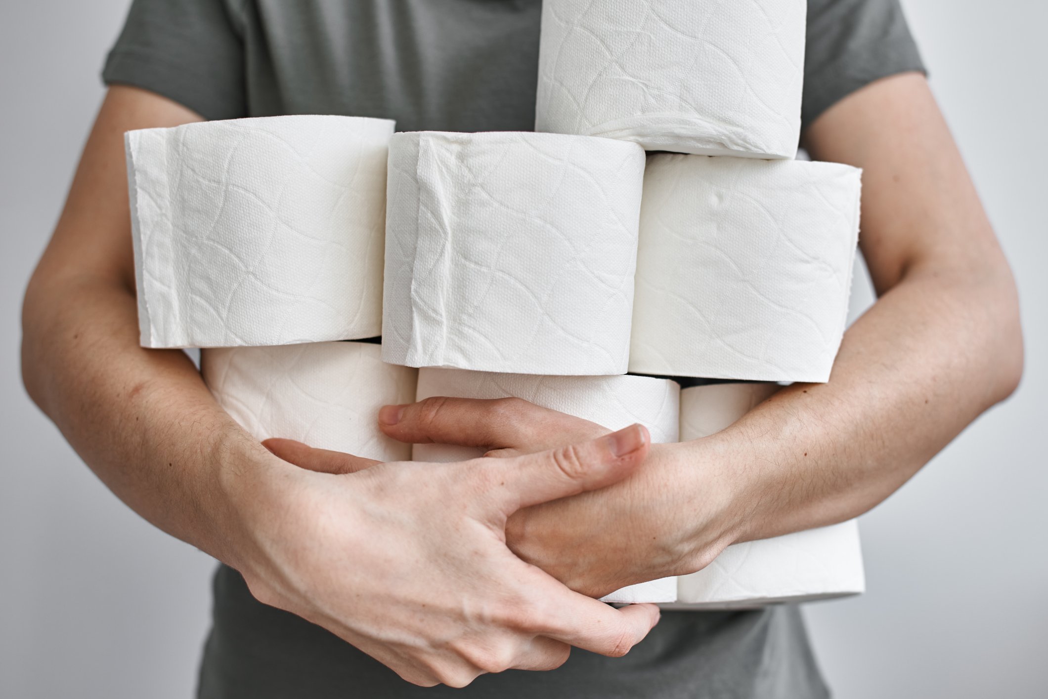 Man holding several rolls of toilet paper.