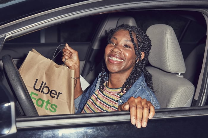 Person in a car holding an Uber Eats bag.