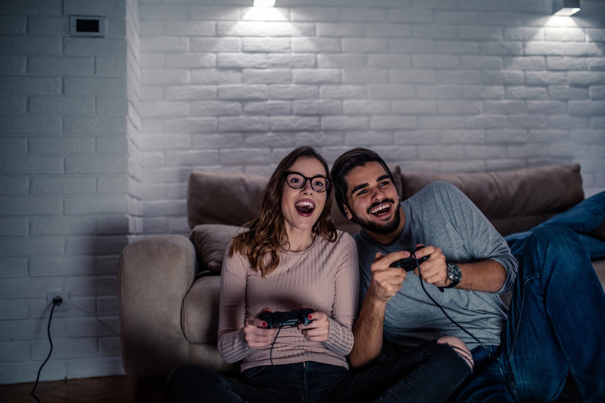 A man and a woman laugh while playing video games.