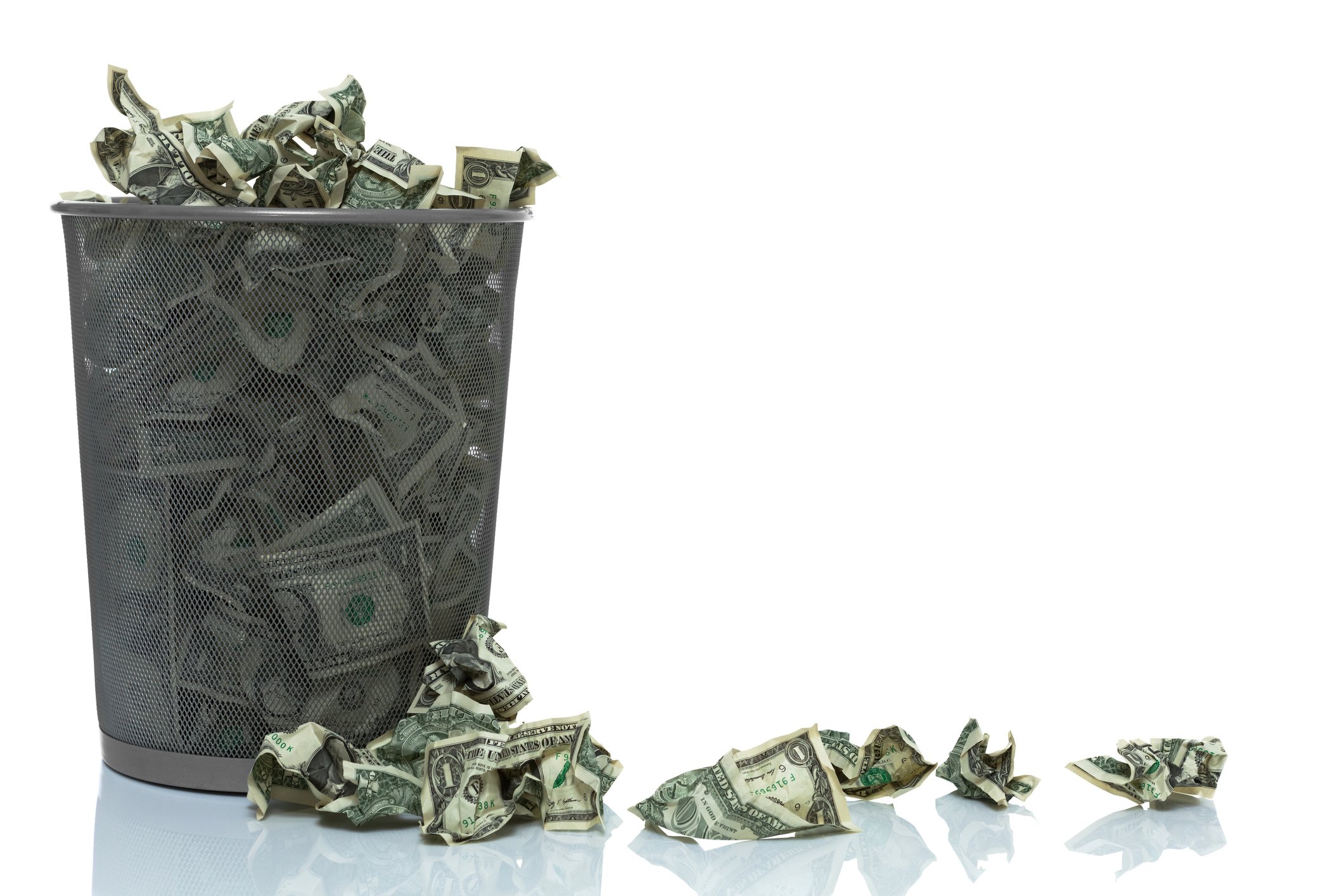 A trash can filled with money, with bills on the floor next to it.