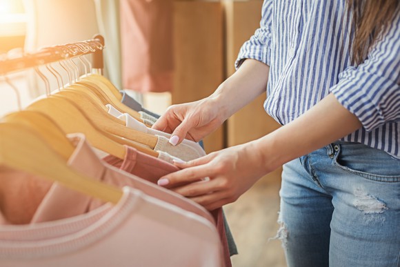 A woman browsing a rack of tops.