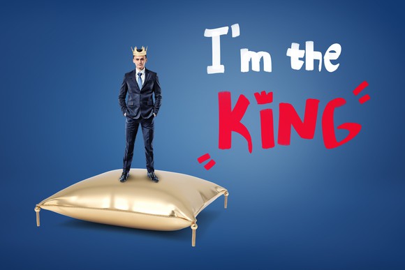 Businessman wearing a crown while standing on a pillow saying "I'm the king."