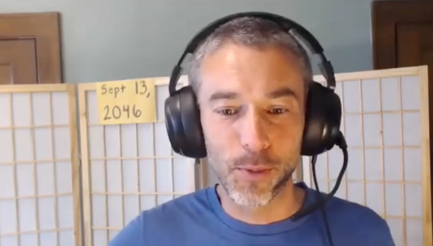 Picture of author wearing headphones with a sign behind him that says Sept. 13, 2046.