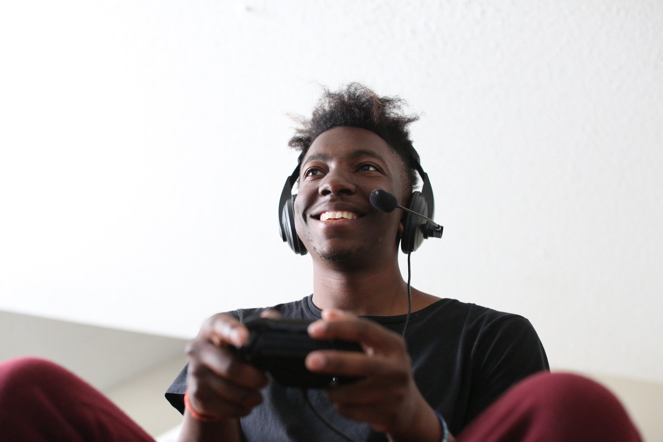 A young man wearing a headset and playing console video games.