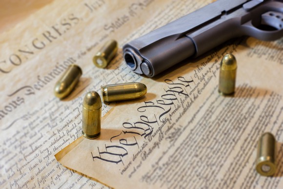 Gun and bullets on a copy of the U.S. Constitution.
