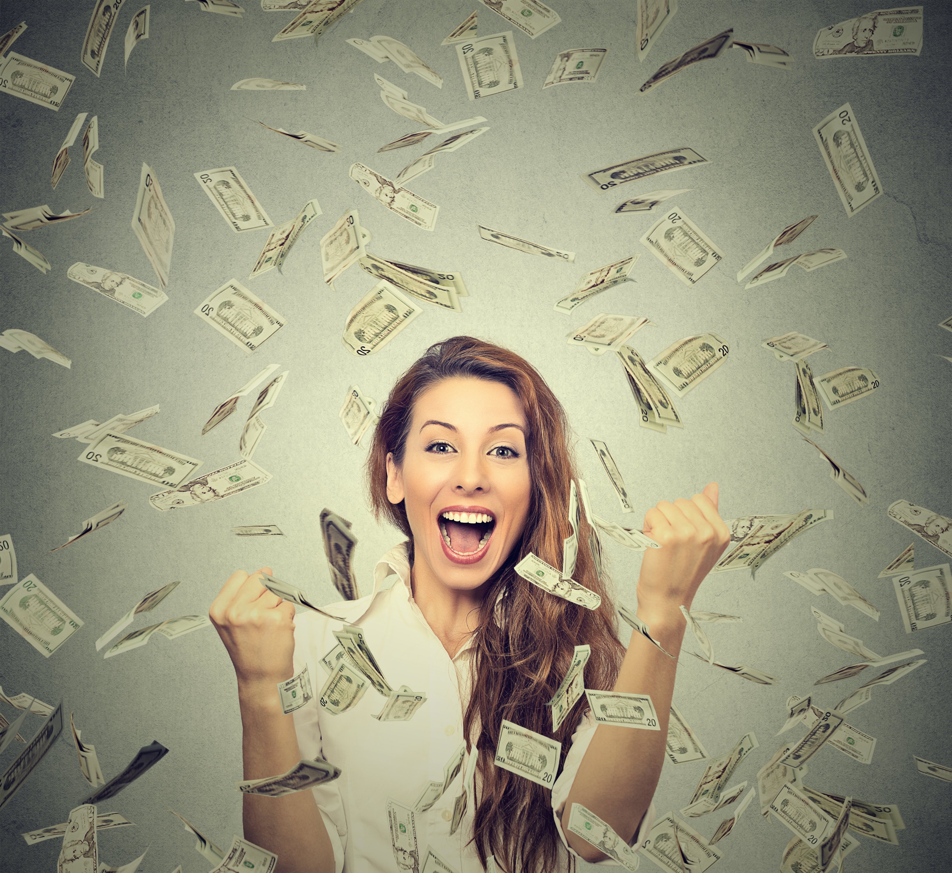 A woman smiles as money floats in the air around her.