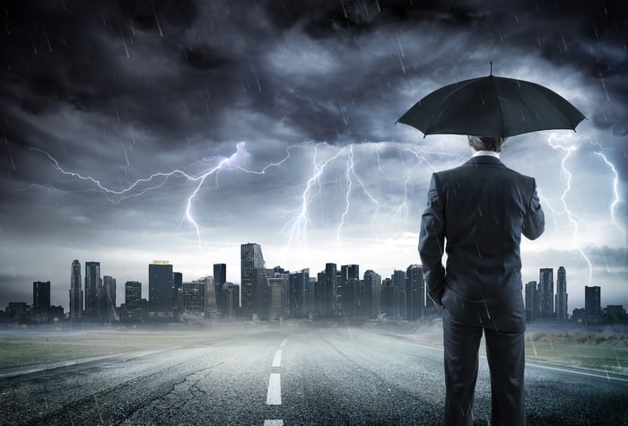 Man in a suit holding an umbrella, looking at a cityscape, as a lightning storm rages overhead