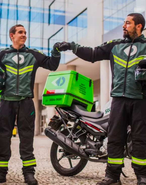 Two men standing in front of a StoneCo branded motorcycle giving each other a fist bump.