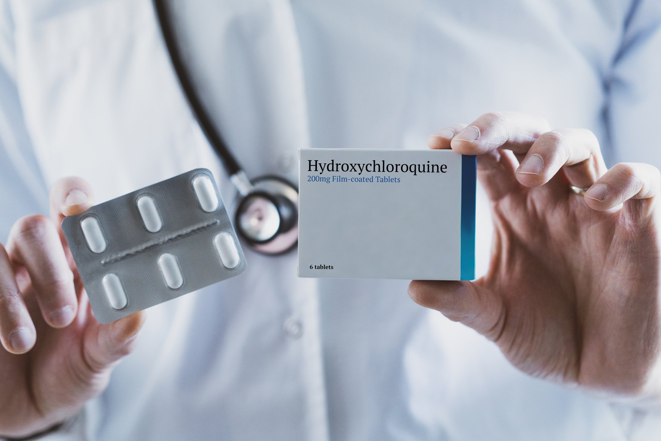A doctor holds a box of hydroxychloroquine pills.