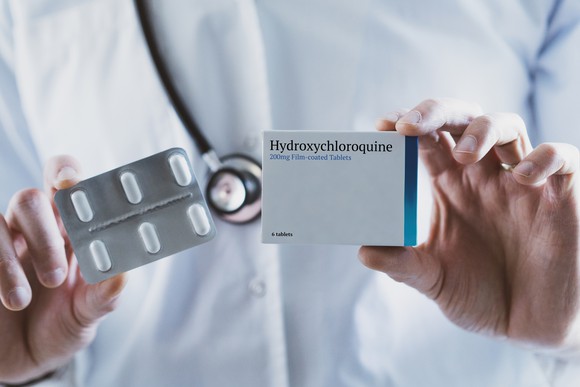 A doctor holds a box of hydroxychloroquine pills.