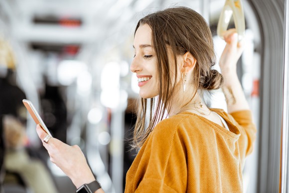 A young woman uses a smartphone while taking a train.