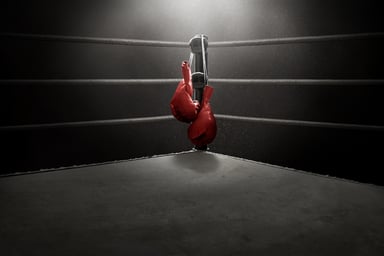boxing gloves hang in the corner of a boxing ring