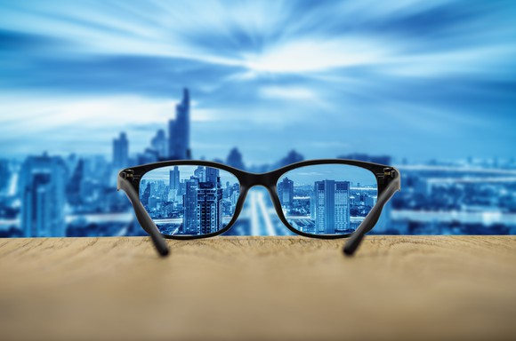 A pair of glasses on a ledge overlooking a city.