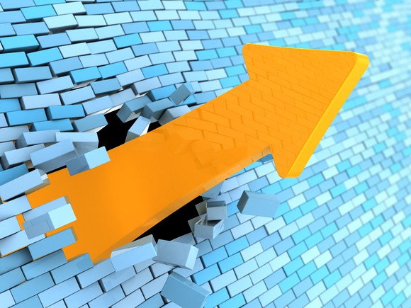 A yellow arrow crashes upward through a blue brick wall.