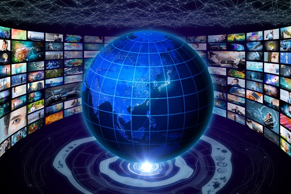 A globe centered on China with a concave wall of TV screens circling around it. 