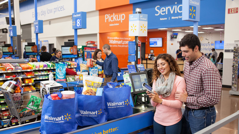 A couple with bagged groceries in the checkout line. 