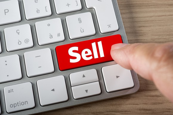 Finger pressing red sell button on keyboard